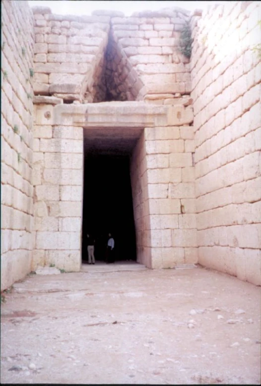 two men stand inside an out door in a wall made from bricks