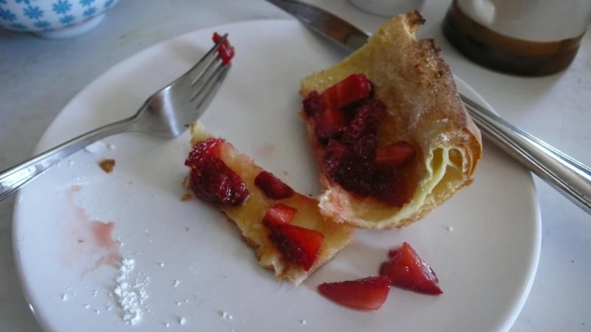 a white plate holding a piece of cake and strawberries