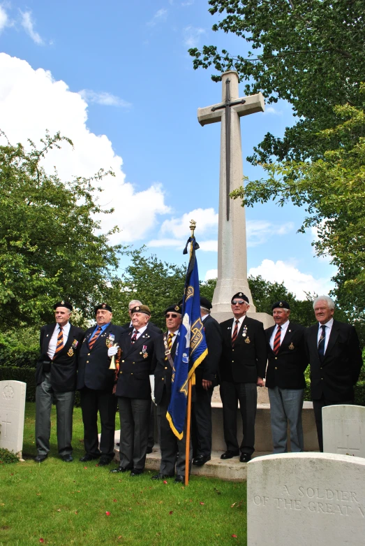 men standing in front of a large cross at a cemetery