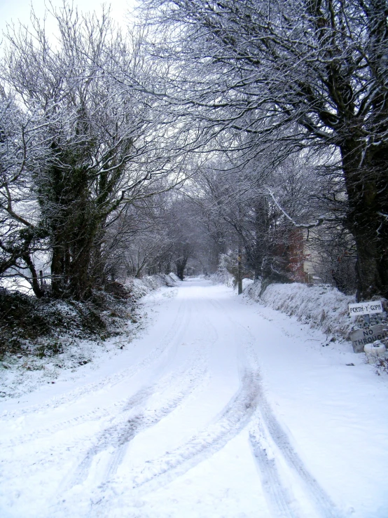 a snow covered street has tracks in the snowy