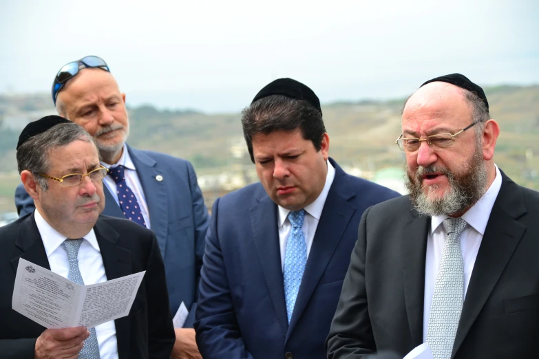 group of men in suits looking at papers