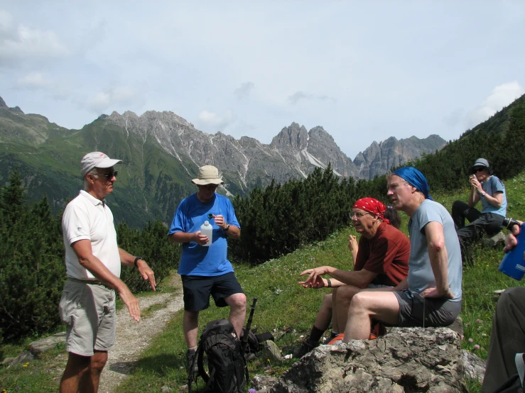 four people gather on top of a hill near some woods