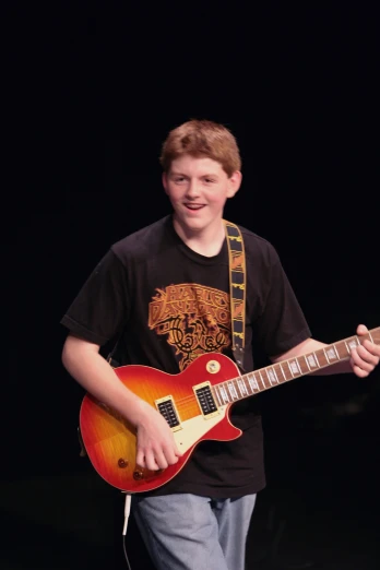 a young man with a guitar smiles and plays