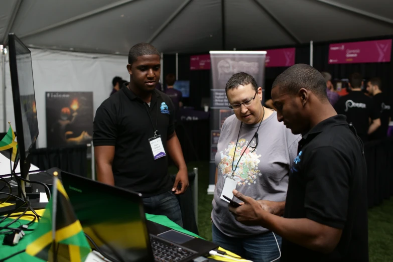 a man standing next to two women holding a laptop computer