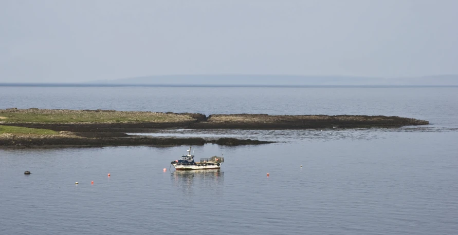 a boat traveling on a lake with rocks in the background