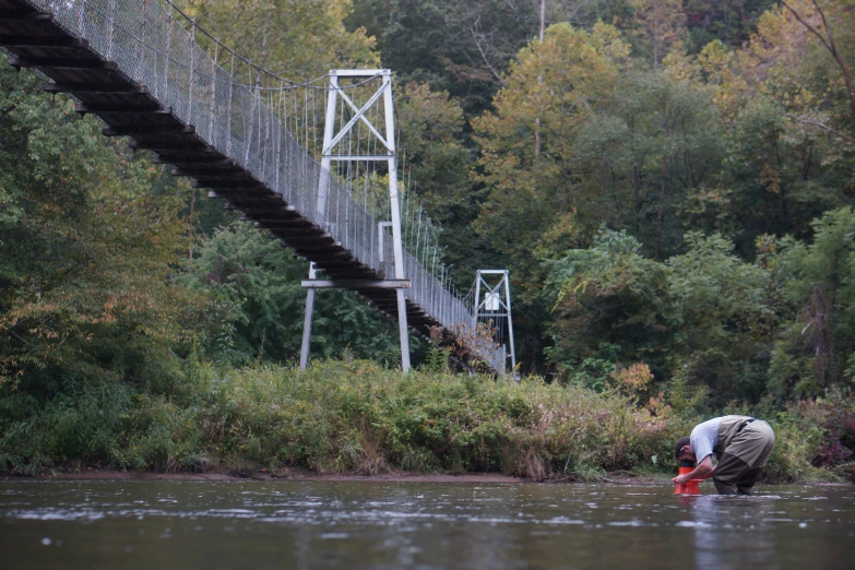 someone crouches on their knees to catch a fly fisherman's fish