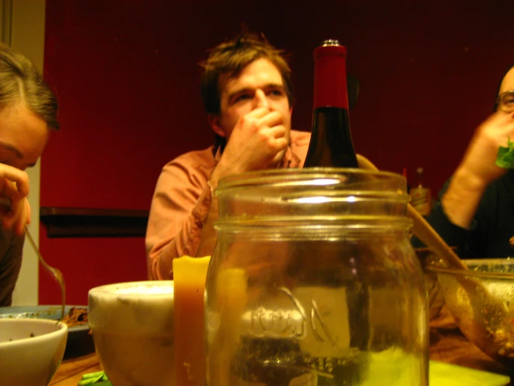two men are talking in front of a glass jar filled with ice