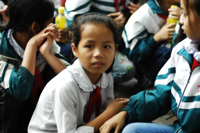 two girls in school uniforms with their backpacks and a cup