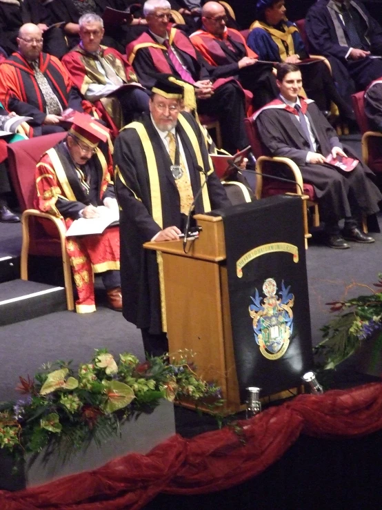 the men are all dressed in robes and are standing at the podium