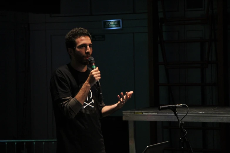 man holding a microphone is standing up in front of a screen