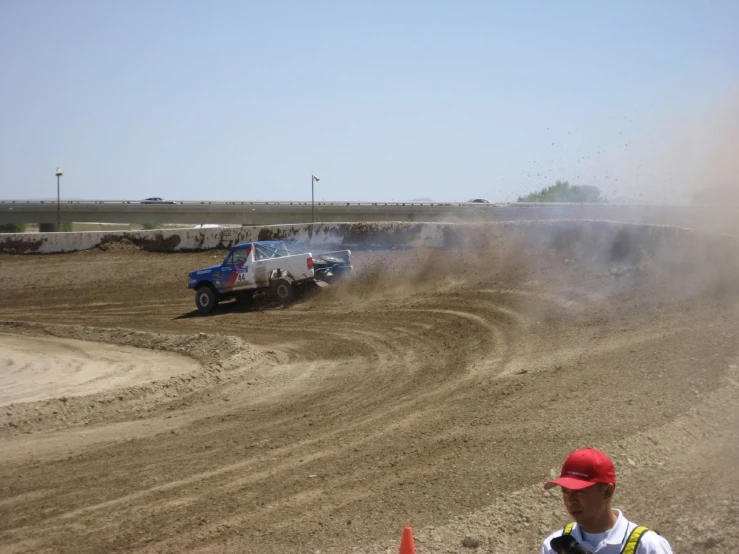 a truck and two men on dirt road with vehicles in the distance