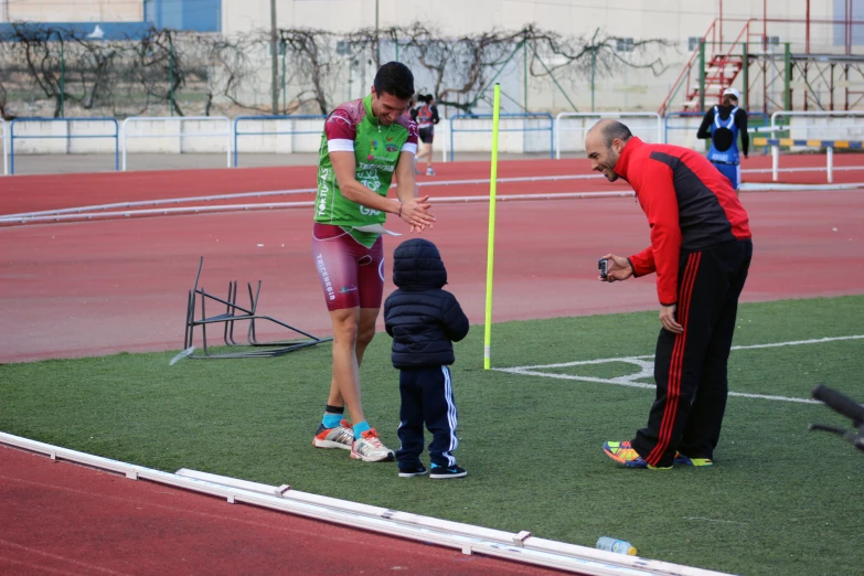 a man and woman holding a child on a field