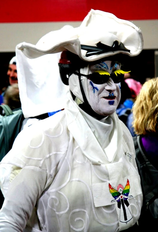 a person wearing white with face paint and a hat