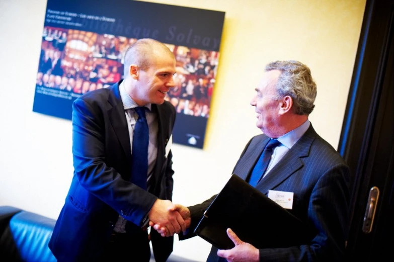 two men in suits shaking hands in an office