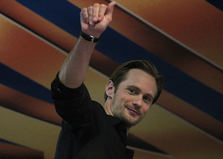 man raising his hand up and looking into the camera