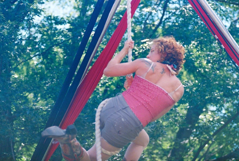 a woman with  on is standing on one leg in an aerial rope course