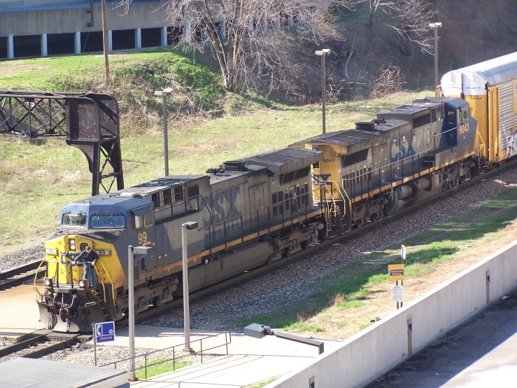 two trains, each yellow and gray, are parked on railroad tracks