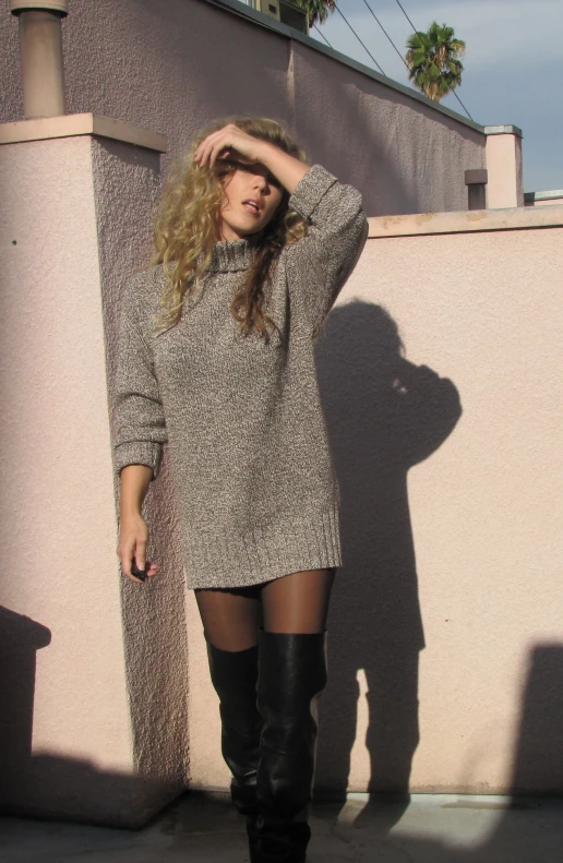 woman in tight stockings and black boots posing by wall