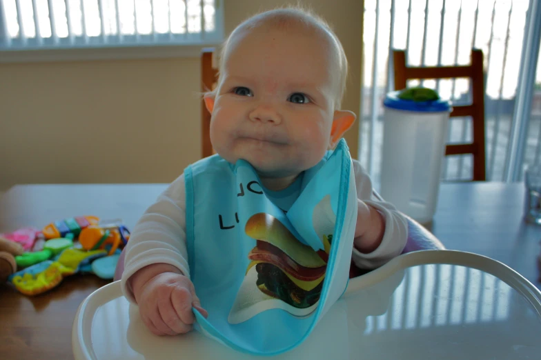 an infant with a bib on sitting at the table