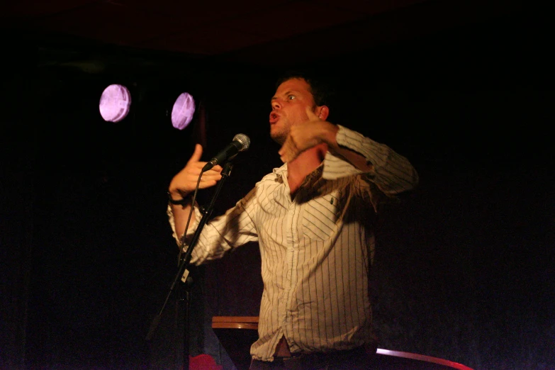 a man in a light and dark shirt holding two microphones