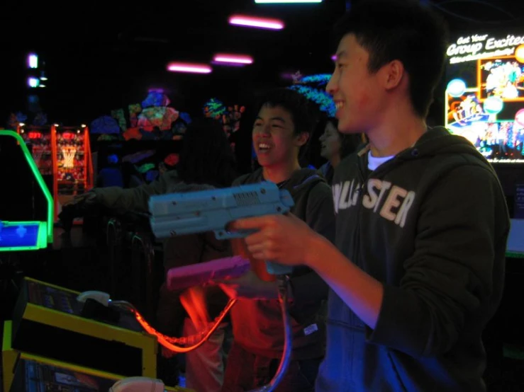 two boys in a pinball game playing with an interactive gun