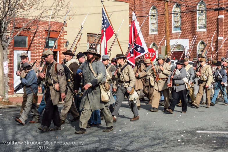 a large group of people in historical uniforms walking past flags