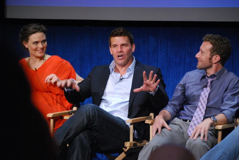 three people are sitting in chairs with their hands out