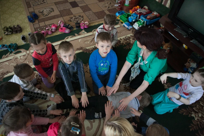 a group of children and adults sit on the floor looking at their laptops