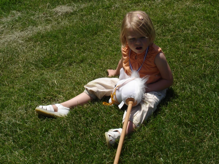 a child sitting on the grass and holding a stick