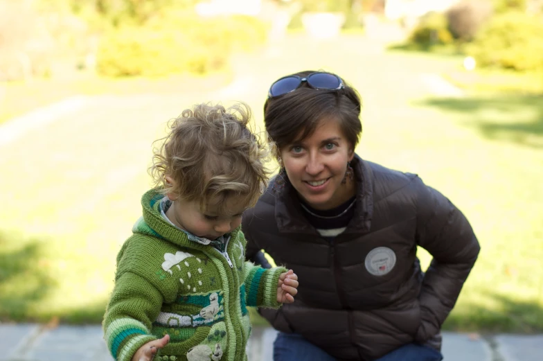 a woman in black jacket sitting on a bench next to a small child