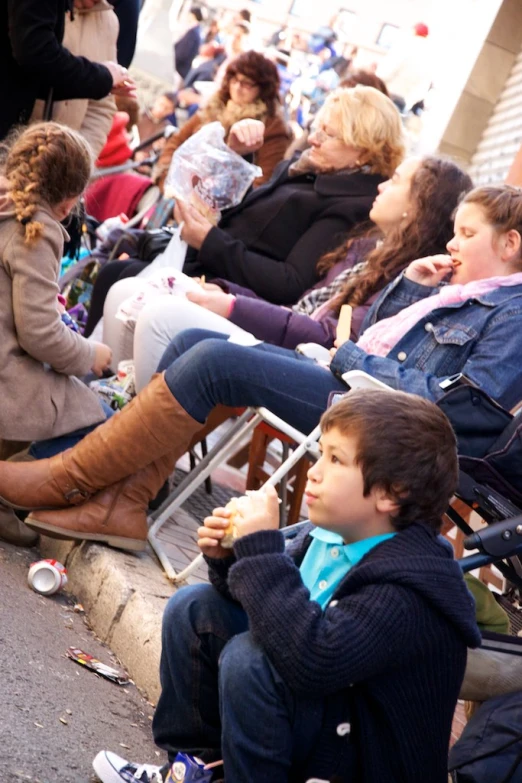 children sit in chairs while adults watch from the street