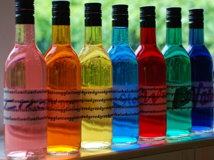 six bottles of different colored liquid sitting next to each other