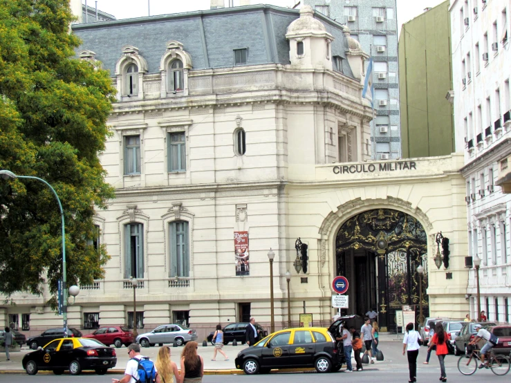 pedestrians and cars in front of a large building