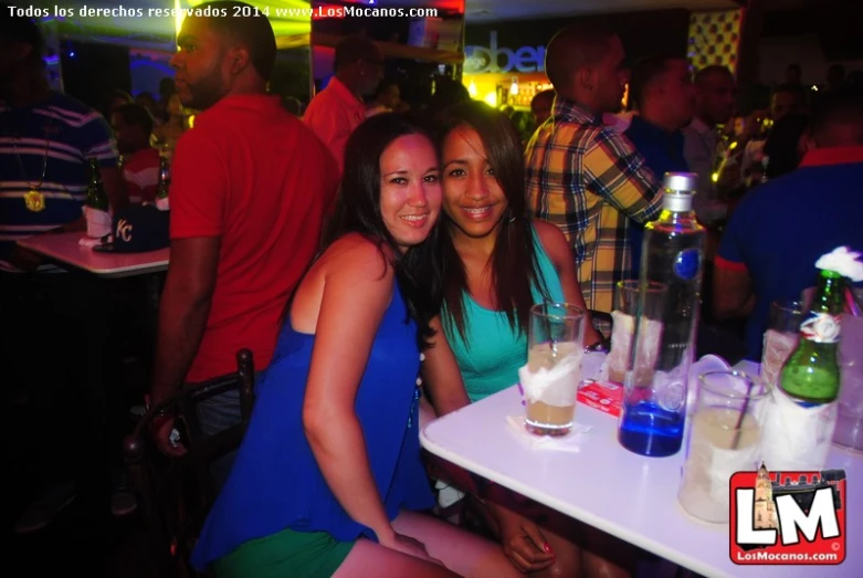 two women smile while posing in front of glasses