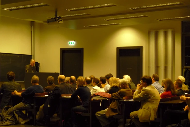 people at tables are gathered in front of a lecture hall