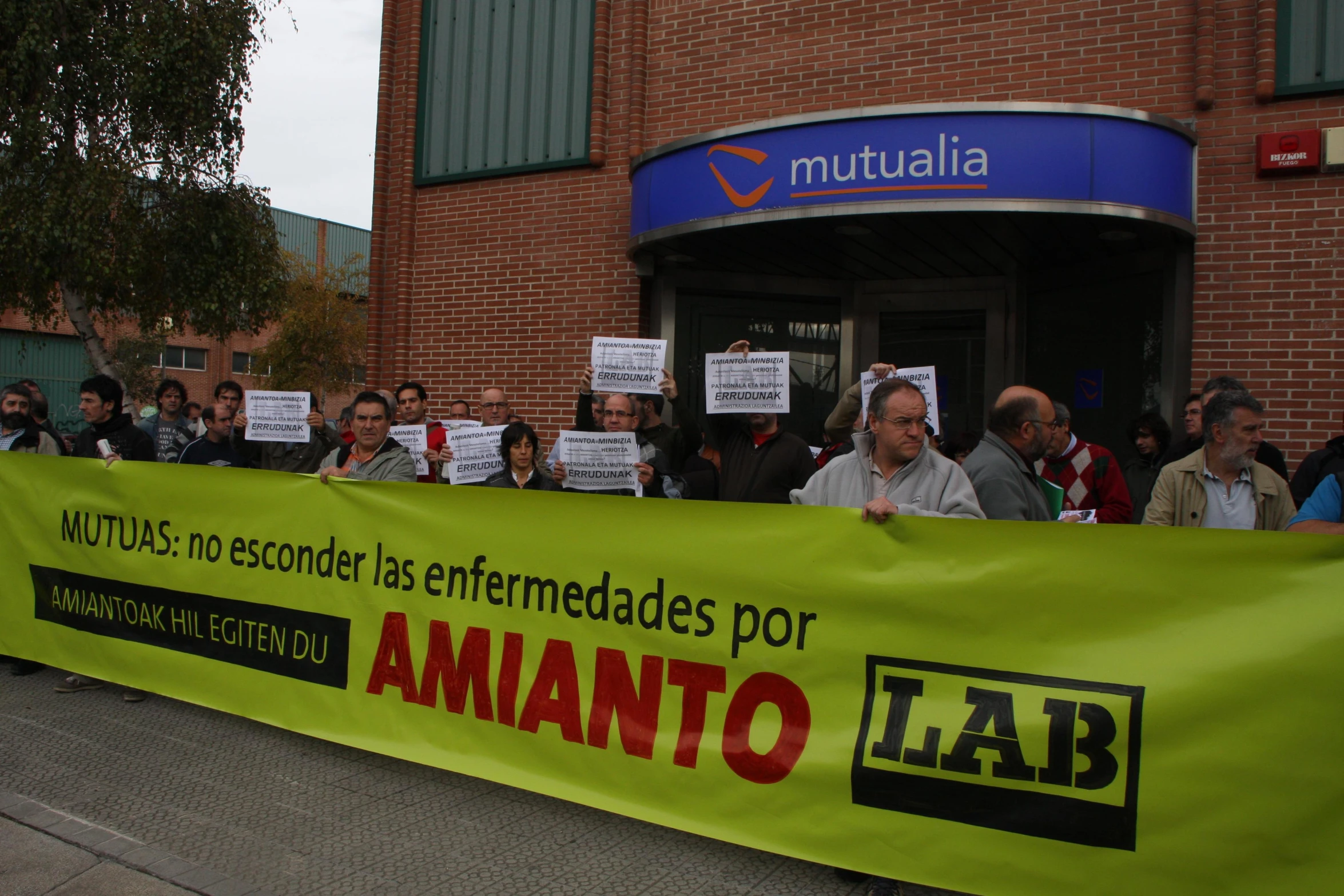 a large yellow sign saying amantoo is protesting for a new courthouse