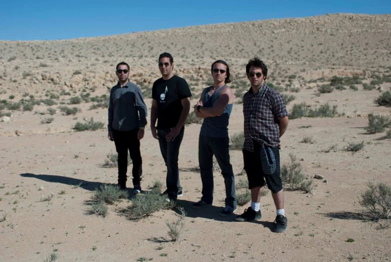 three men posing together in the desert with their hand on each shoulder