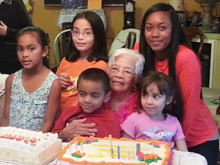 a group of people standing next to a table with cakes on it