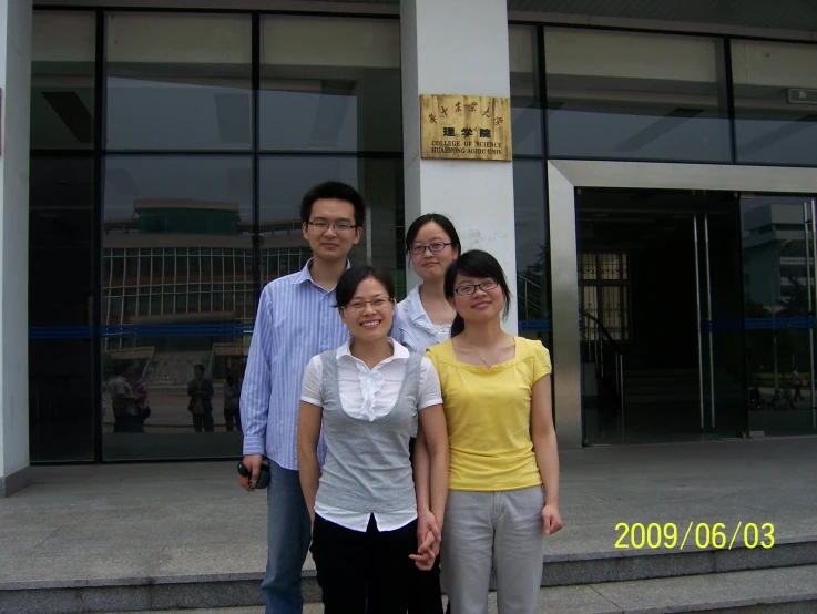 five people posing outside of a building