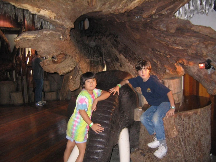 two little girls sitting on an elephant inside a building