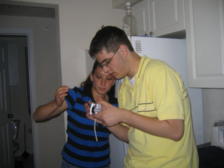 a man and a woman in the kitchen checking the time on their watch