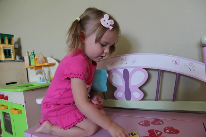  in pink playing with doll furniture in bedroom