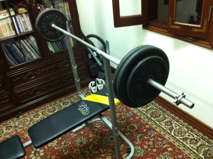 a bench and barbell sit on the carpet