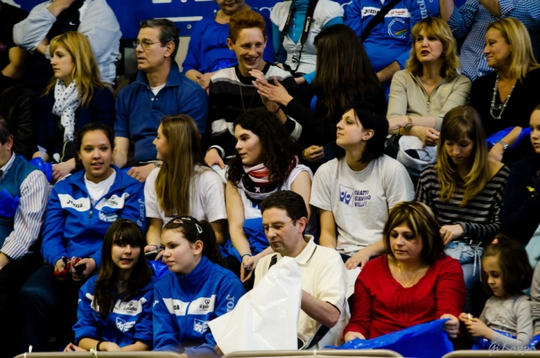 many people seated in chairs watching soing on their phone