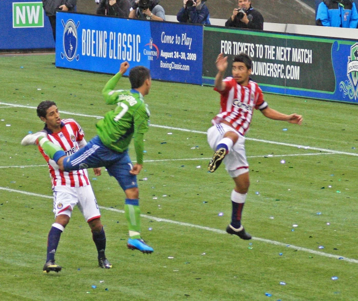 three soccer players during a match on a green field