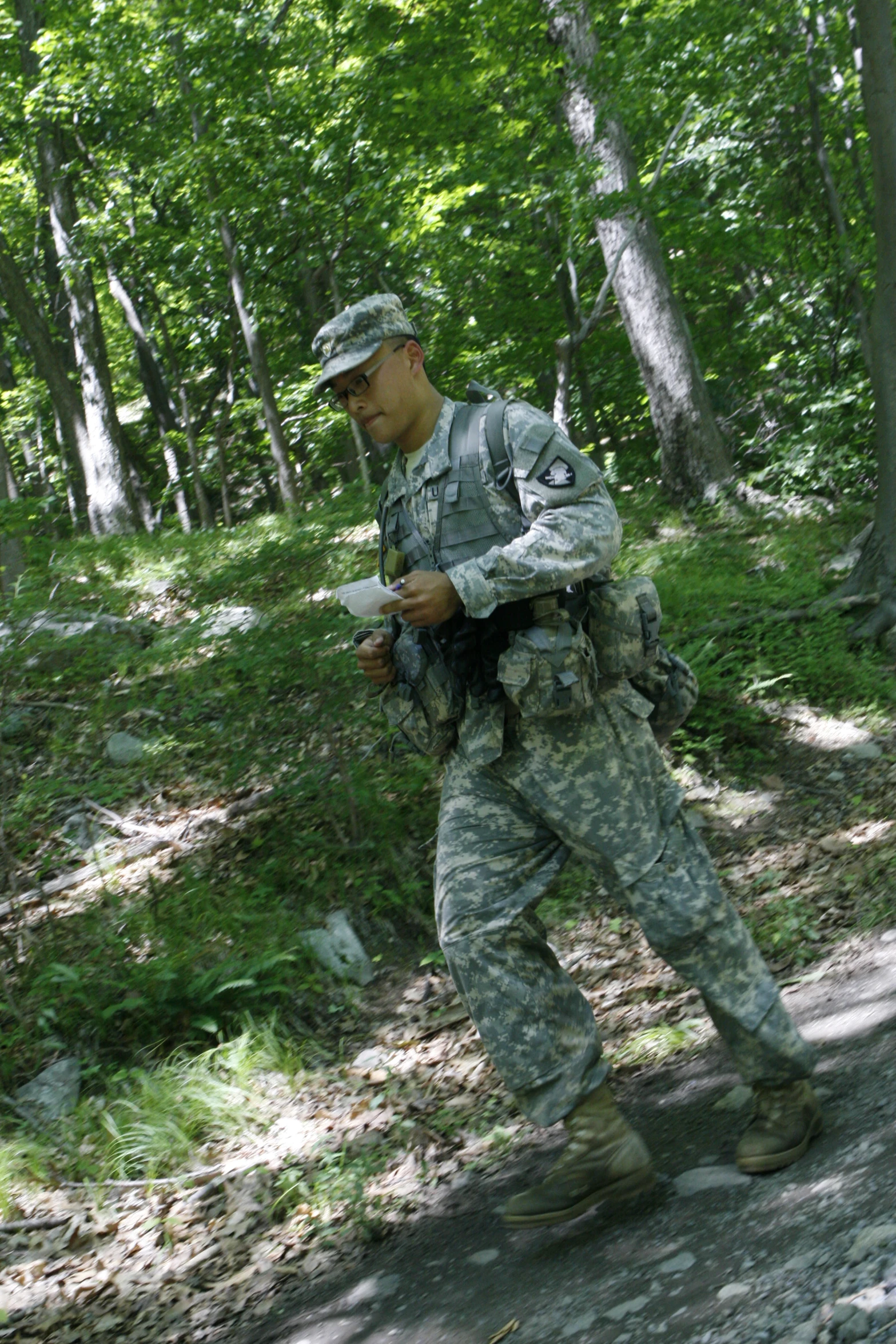 a soldier stands in the woods while reading a book