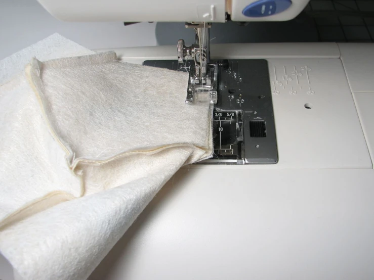 the white piece of fabric is being sewn on