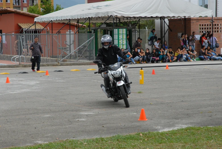 a man riding a motorbike past orange cones