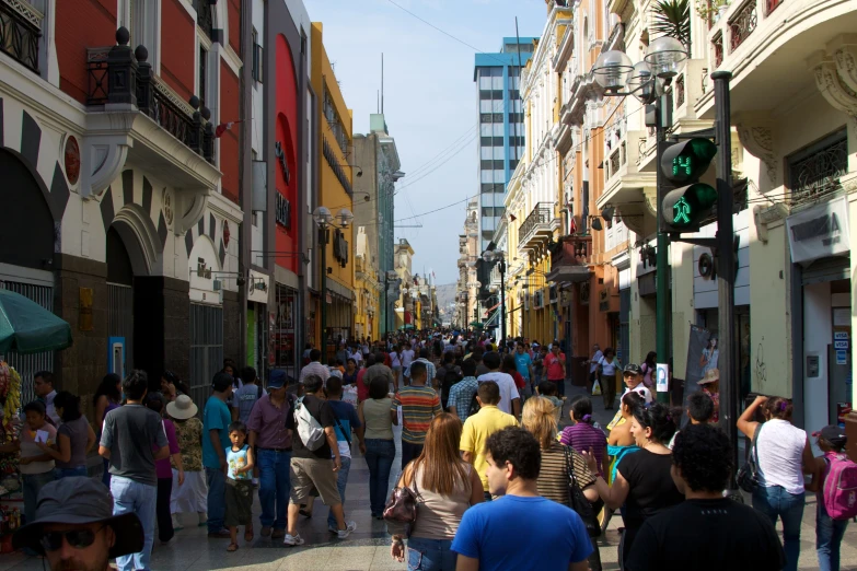 many people walking down a street with tall buildings