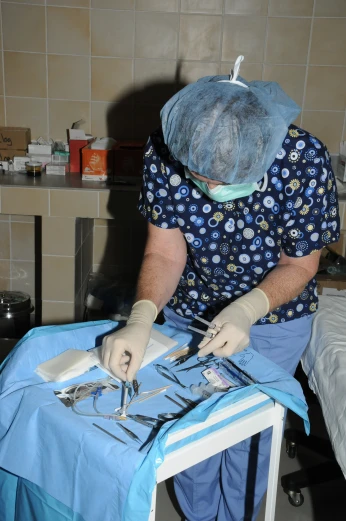 a surgeon wearing surgical gloves and an operating bag while using surgical scissors